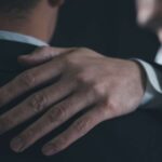 Kondolenz bei Kollegen - Mann legt seine Hand auf die Schulter eines anderen Mannes, um ihn zu trösten