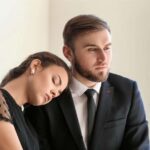 Ein Mann und eine Frau trauern, die Frau lehnt sich an die Schulter des Mannes